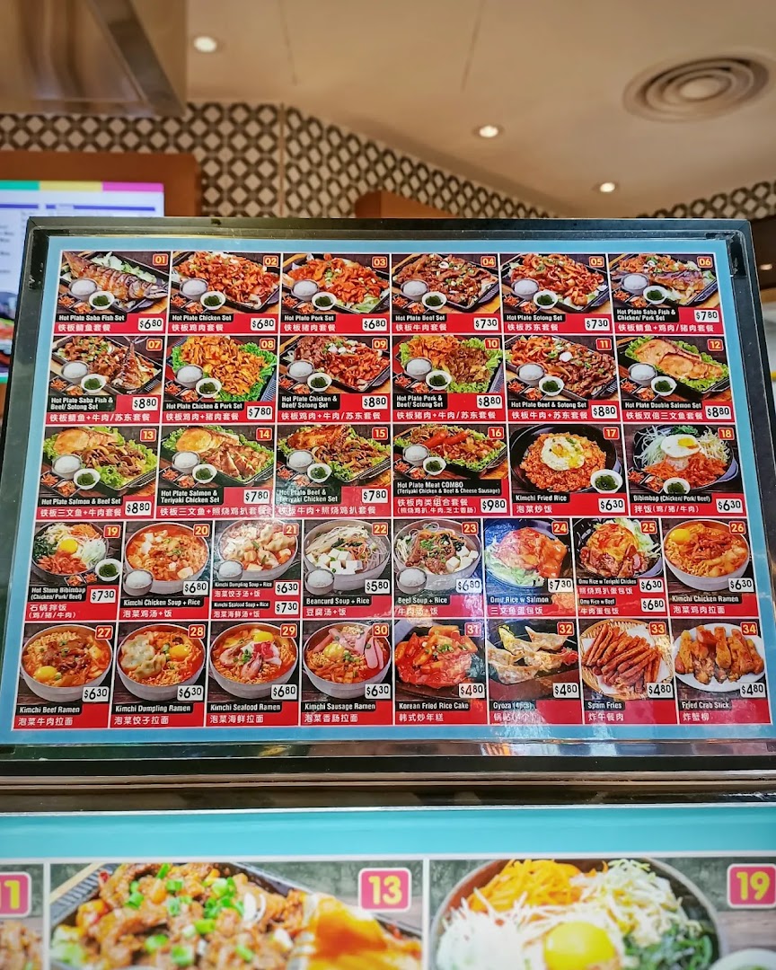 A vibrant menu display showcasing a variety of Korean hot plate sets, rice dishes, soups, ramen, and sides.