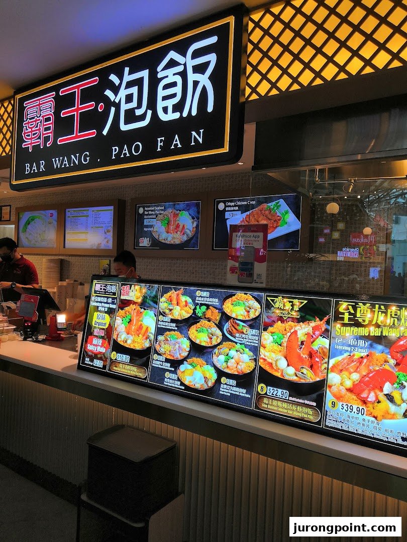 A vibrant food stall interior showcasing a large digital menu display with various Pao Fan dishes.
