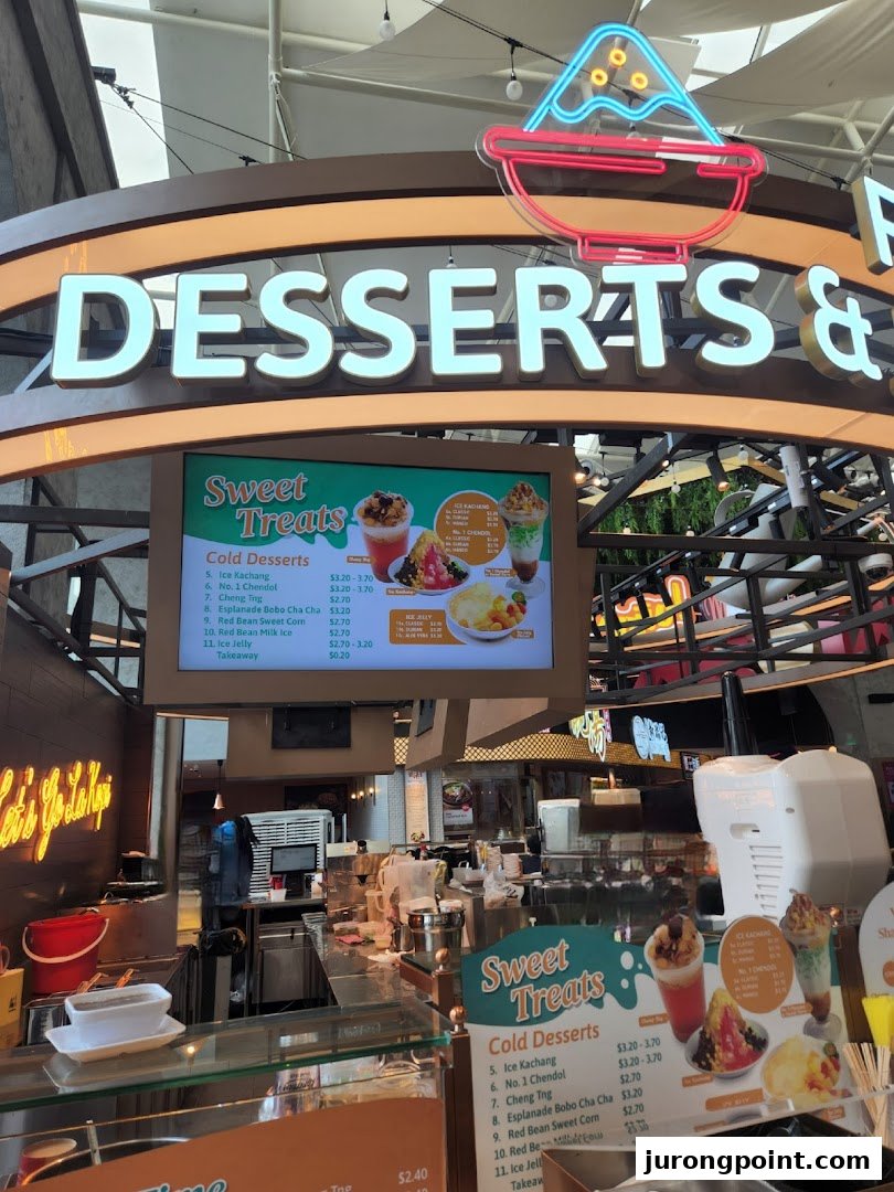 A dessert counter at Kopitiam Food Hall featuring a digital menu board with various cold desserts and prices.