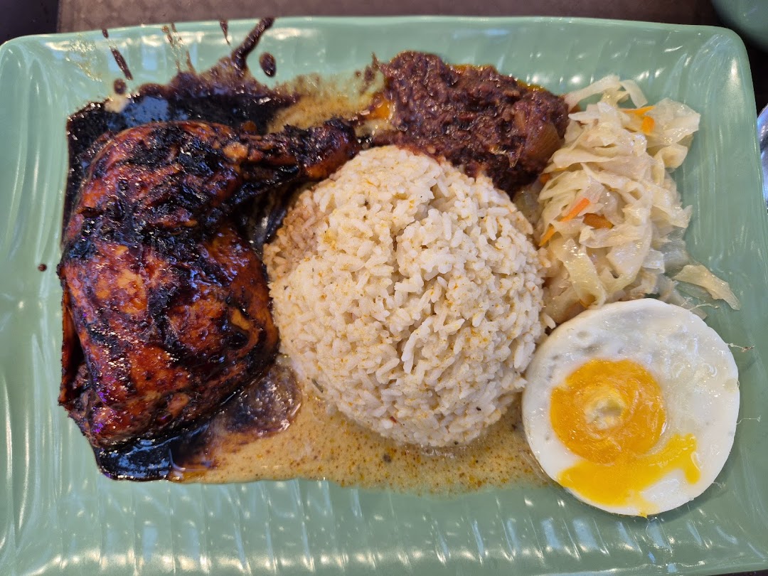 A delicious plate featuring grilled chicken, seasoned rice, vegetables, and a fried egg.