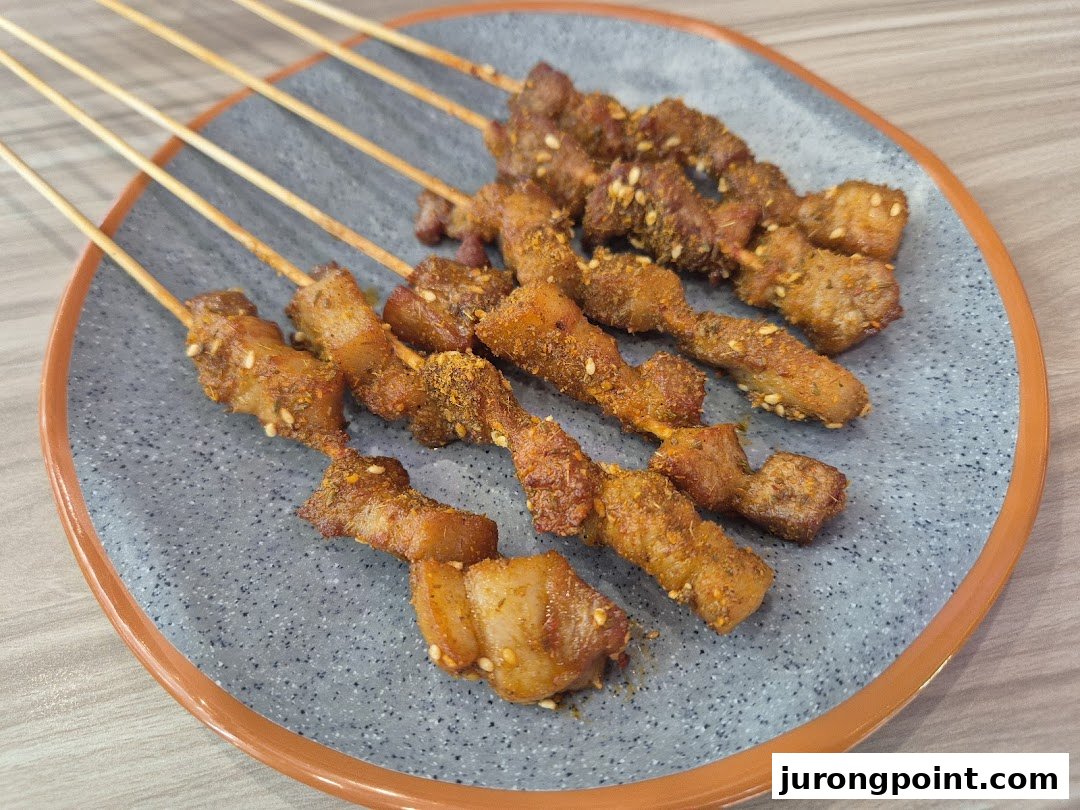 A plate of spiced meat skewers, garnished with sesame seeds and chili flakes.