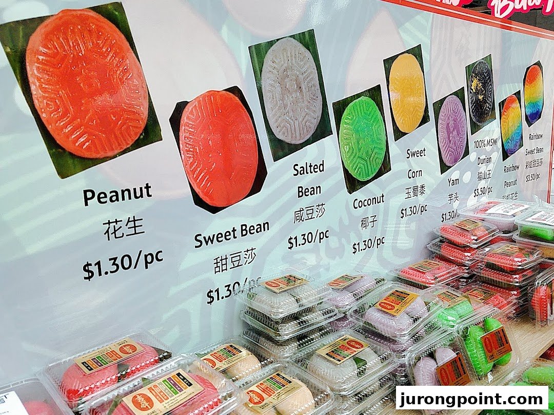 A vibrant display of traditional kueh with various flavors and prices at Kopitiam Food Hall.