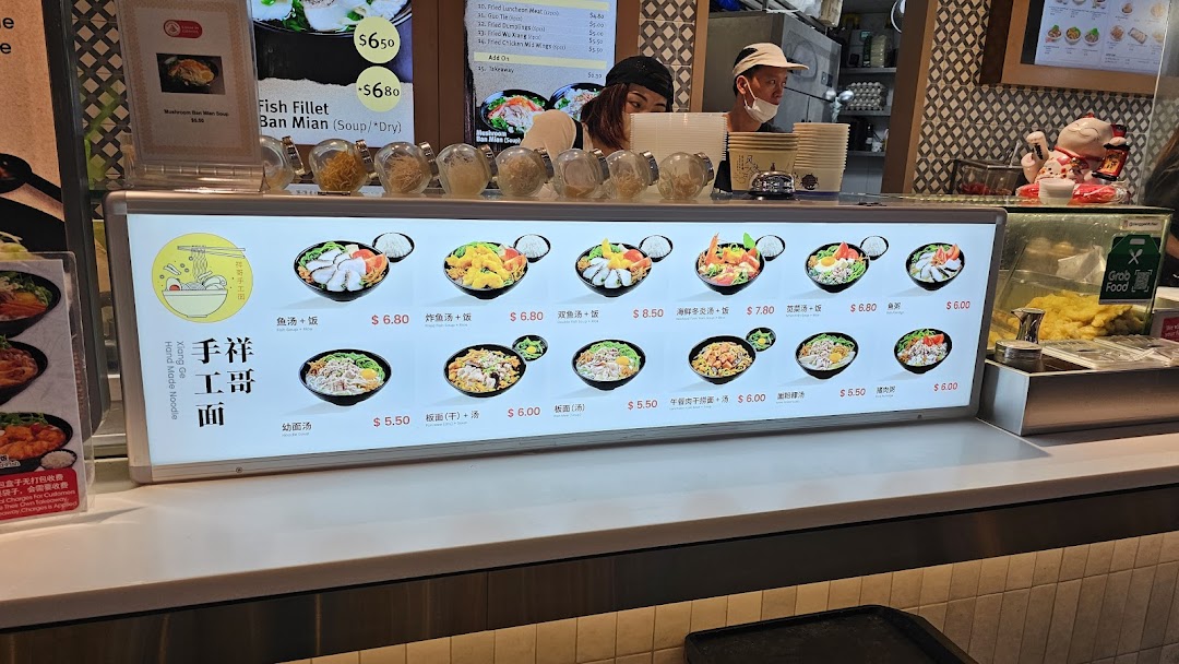 A food stall counter at Kopitiam Food Hall featuring a bright menu display of various noodle and rice dishes.