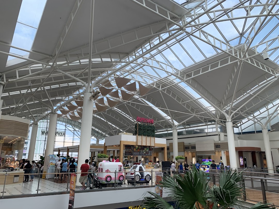 A spacious food hall interior with high ceilings, various food stalls, and people dining.