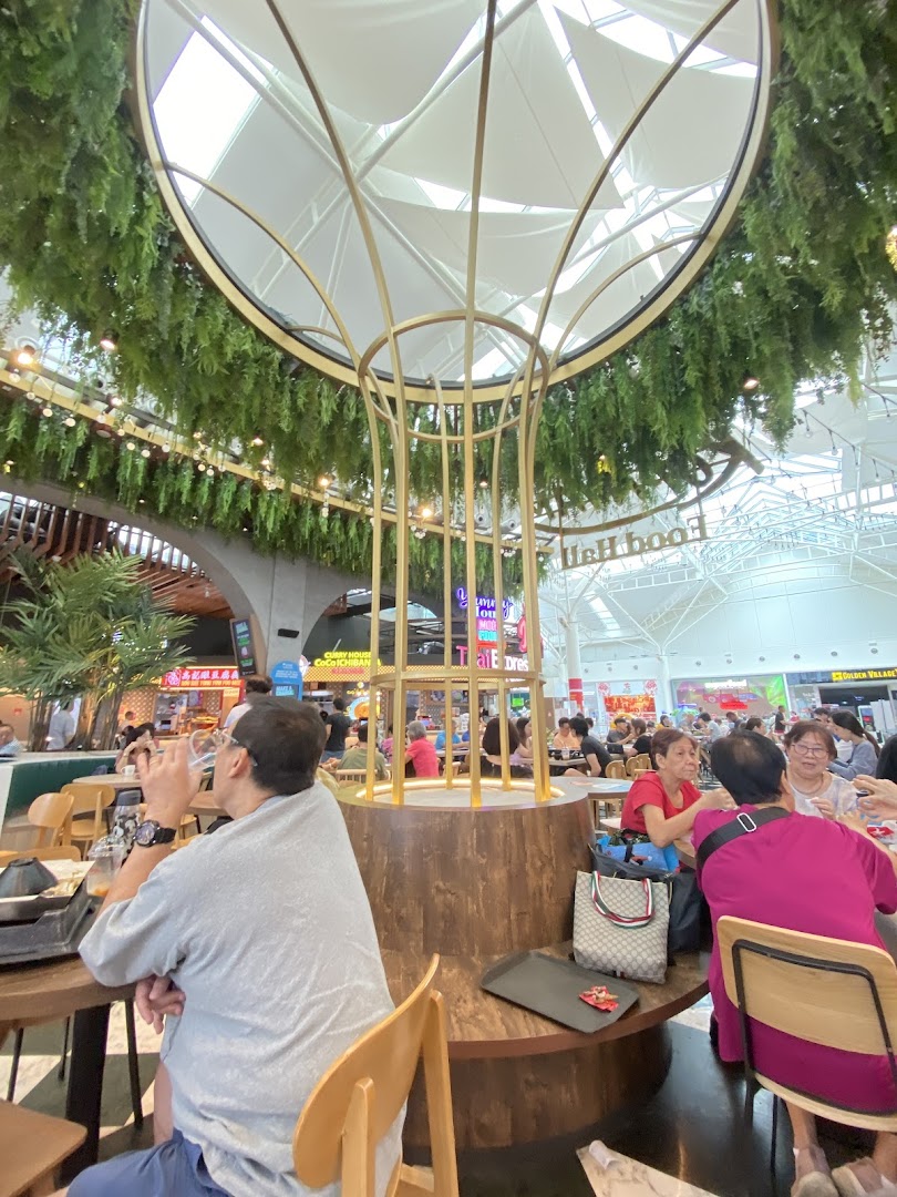 A vibrant interior view of Kopitiam Food Hall, featuring diners and a large decorative centerpiece.