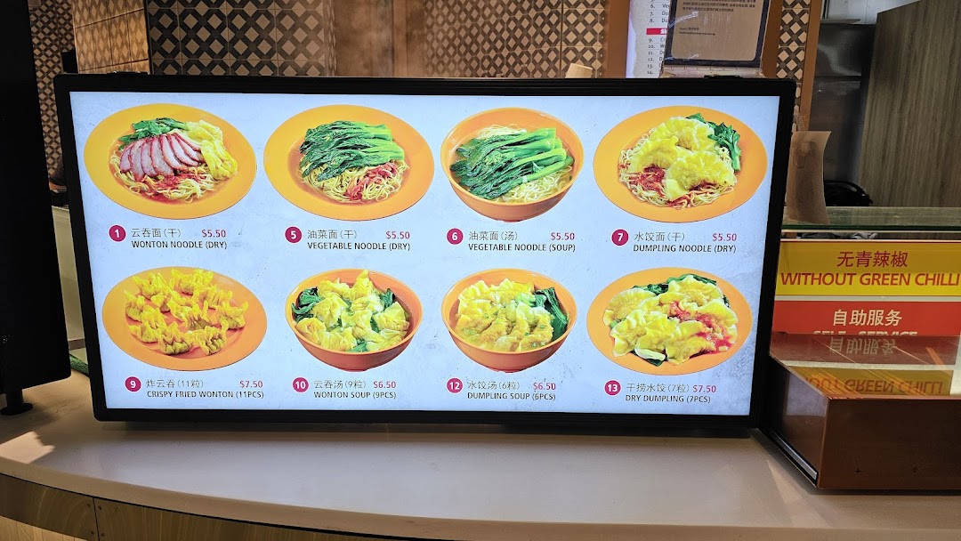 A digital menu board displaying various noodle and dumpling dishes with prices at Kopitiam Food Hall.