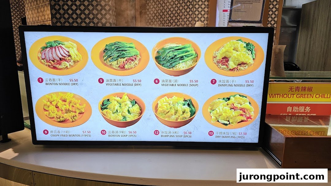 A digital menu board displaying various noodle and dumpling dishes with prices at Kopitiam Food Hall.