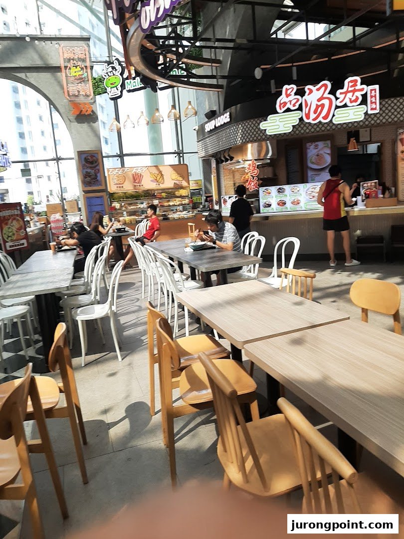 A vibrant interior view of Kopitiam Food Hall with various food stalls and diners.