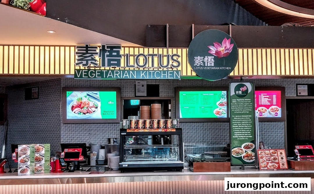 The counter of Lotus Vegetarian Kitchen, featuring digital menus, food displays, and a prominent sign.