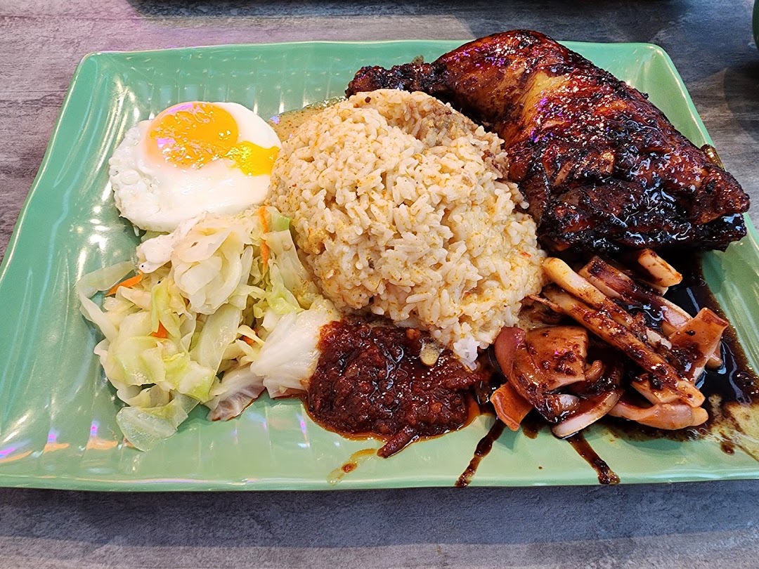 A delicious plate featuring rice, grilled chicken, squid, fried egg, and vegetables.