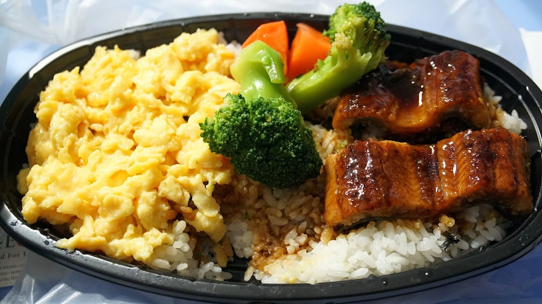 A bento box featuring glazed eel, fluffy scrambled eggs, rice, and steamed vegetables.