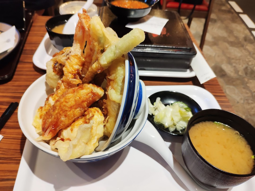A close-up of a delicious Japanese tempura bowl served with miso soup and pickles.