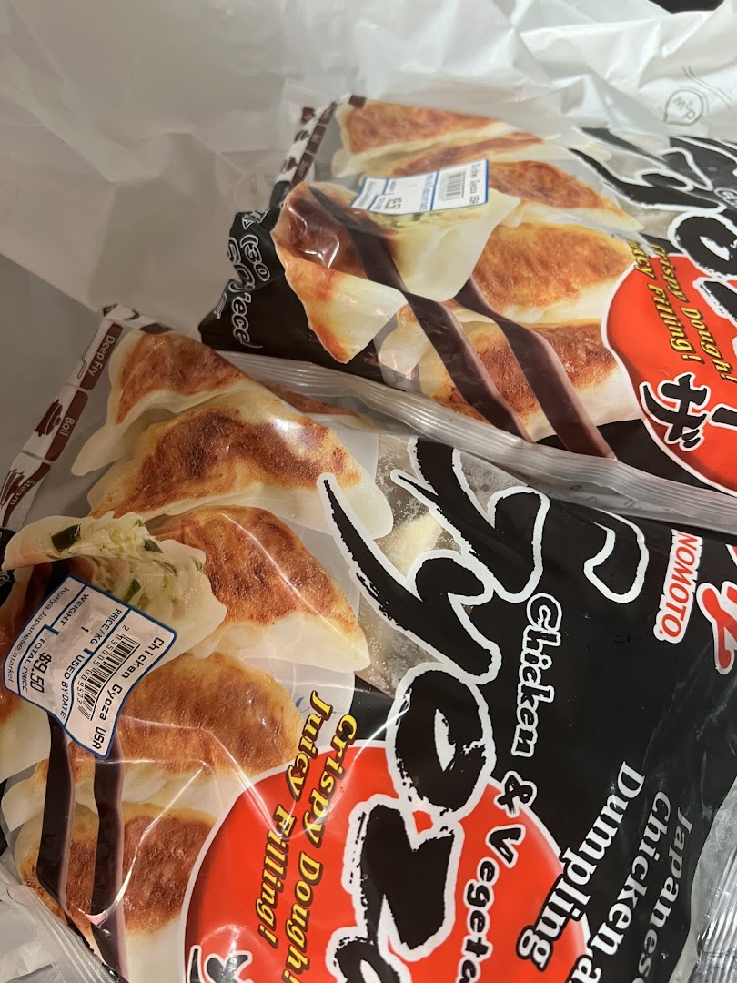 Two bags of frozen Japanese chicken and vegetable gyoza with a price label inside a shopping bag.