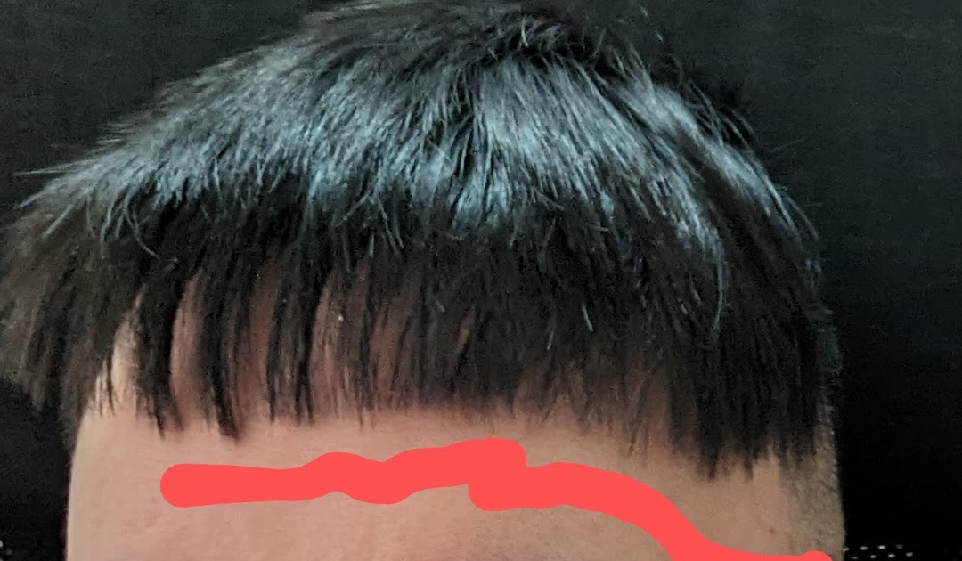 A close-up view of a person's dark hair, showcasing a fresh, precise haircut with a clean fringe.