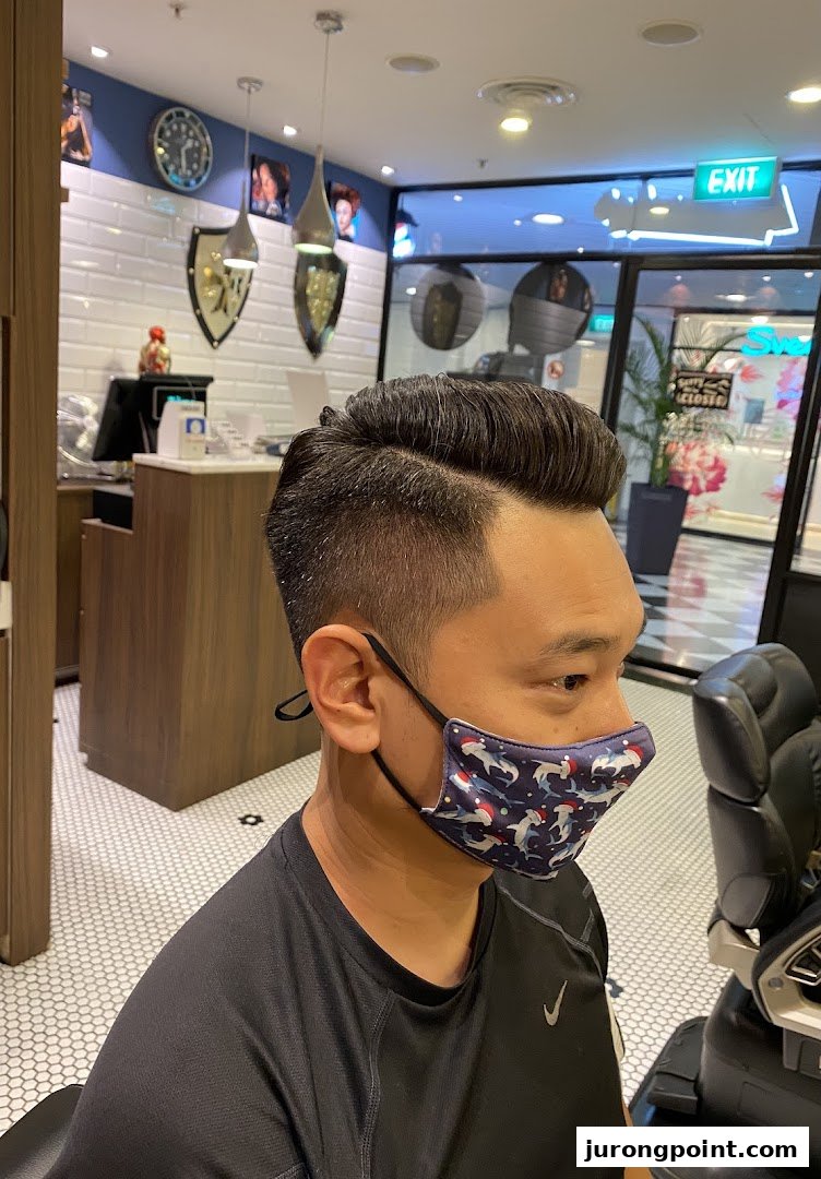 A man with a fresh haircut and fade, wearing a mask, inside LA Barbershop.