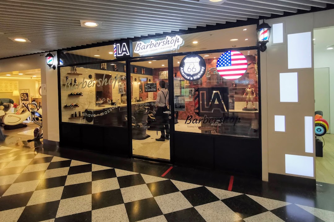 The storefront of LA Barbershop, featuring its entrance, signage, and interior view.