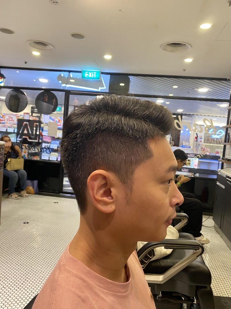A customer showcasing a fresh haircut inside LA Barbershop, highlighting the shop's interior.