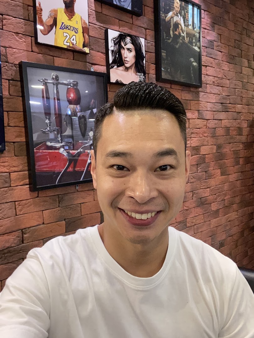 A smiling customer showcases a fresh haircut inside LA Barbershop, featuring stylish wall decor.