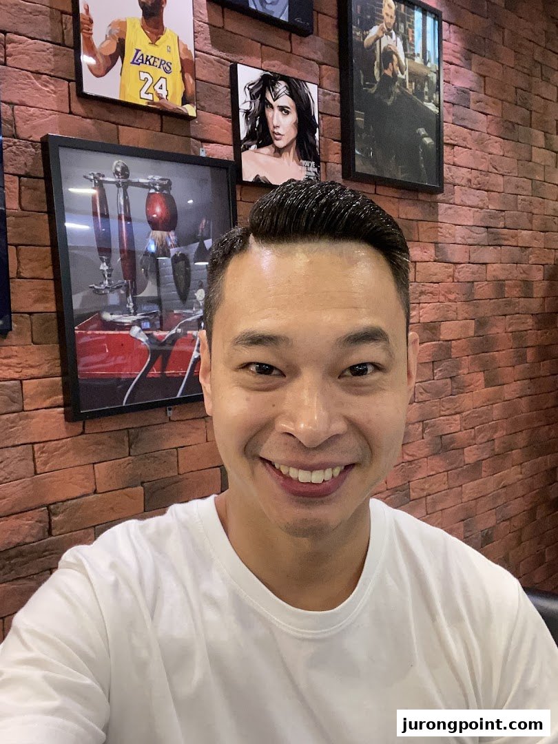 A smiling customer showcases a fresh haircut inside LA Barbershop, featuring stylish wall decor.
