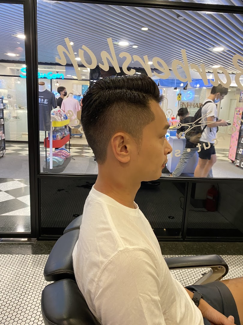 A customer showcasing a fresh haircut inside LA Barbershop, with the mall environment visible outside.