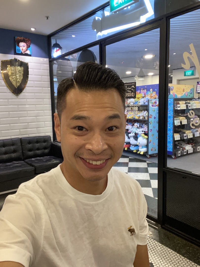 A smiling man inside LA Barbershop, showcasing the shop's stylish interior and a fresh haircut.