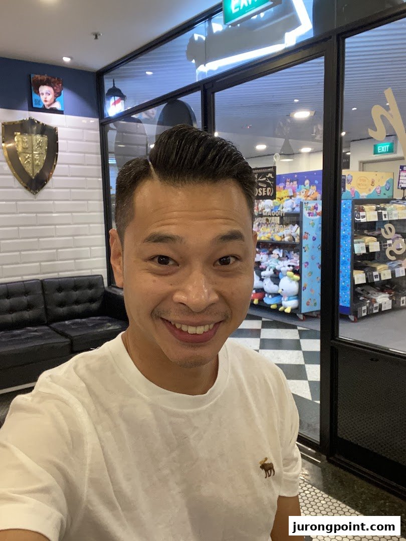 A smiling man inside LA Barbershop, showcasing the shop's stylish interior and a fresh haircut.