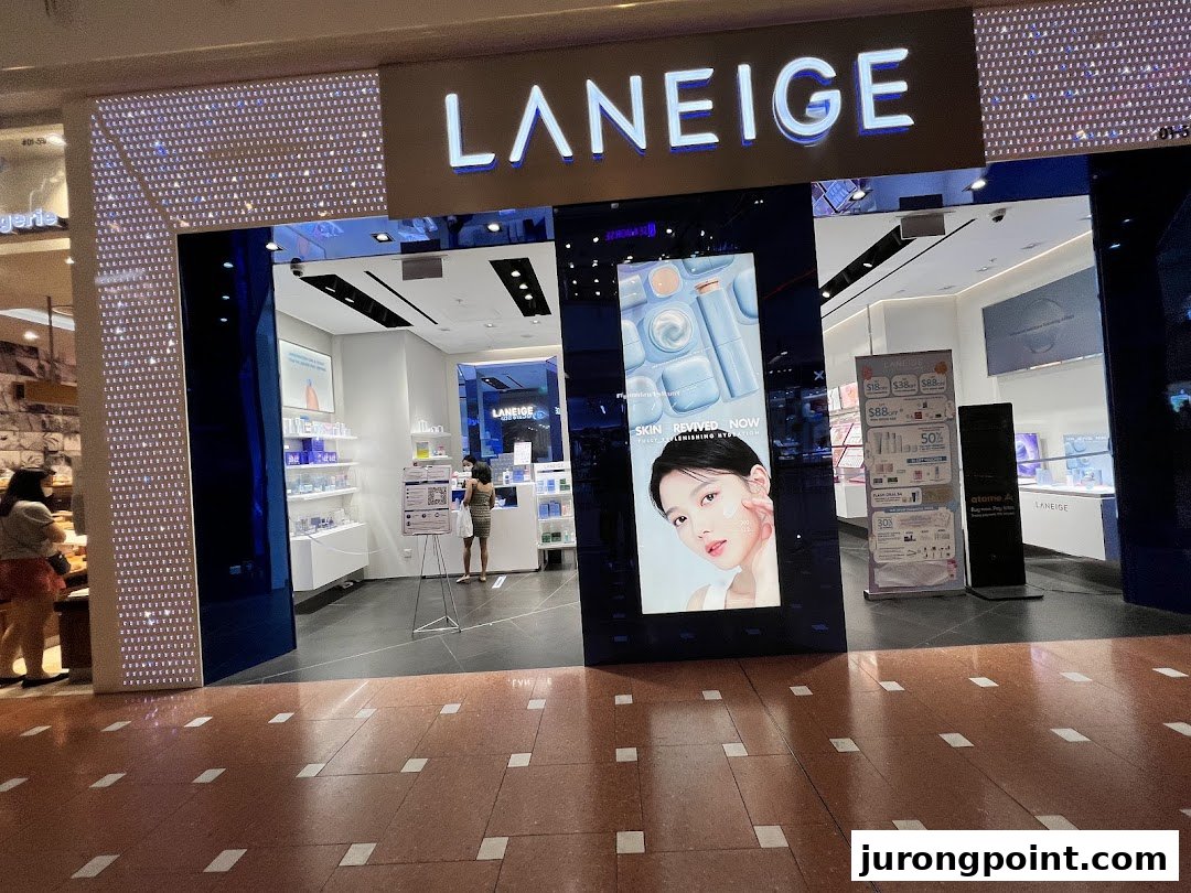 The illuminated storefront of LANEIGE beauty shop, featuring product displays and a digital screen.