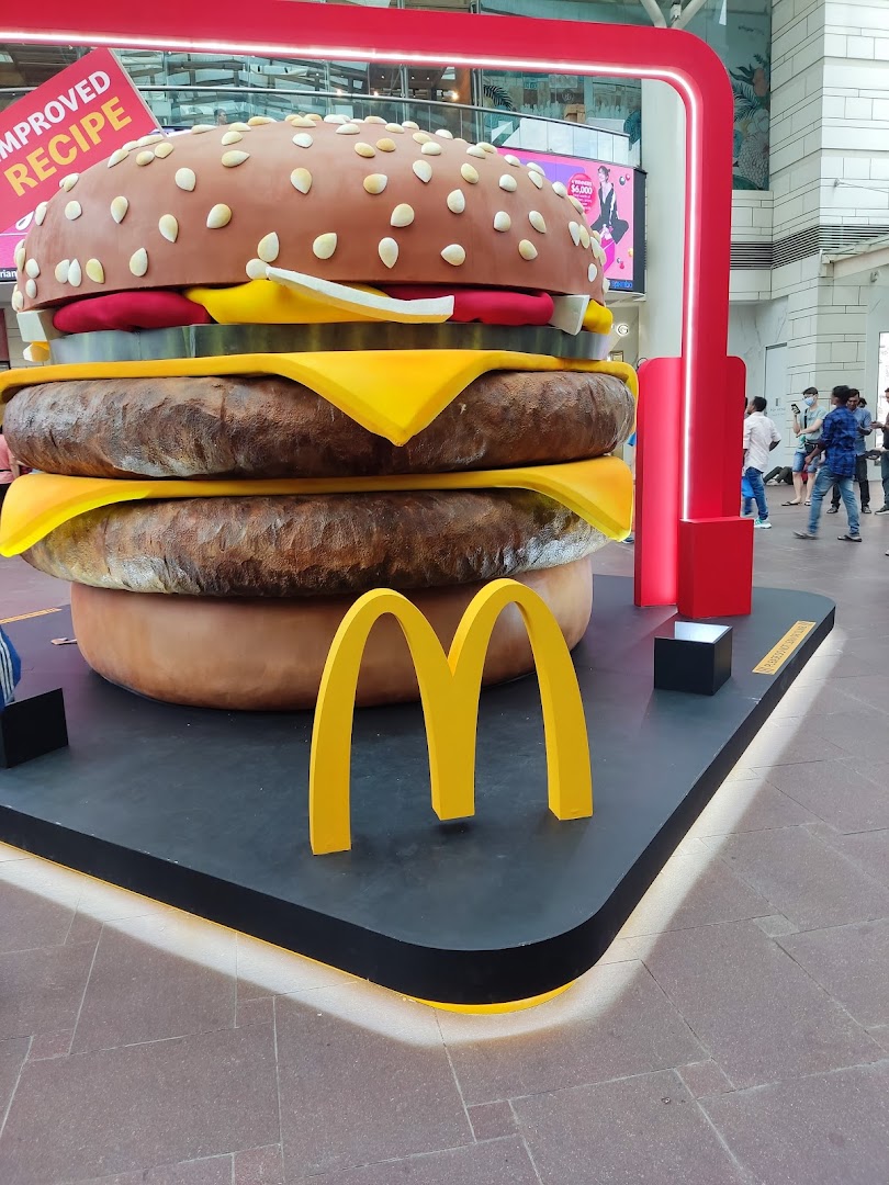 A giant McDonald's burger display with the golden arches, promoting an improved recipe.