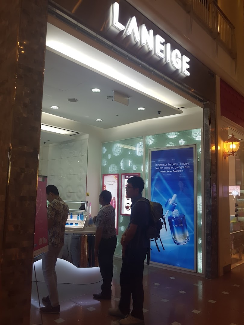 The illuminated entrance of a LANEIGE beauty shop, showcasing its branding and interior with customers.
