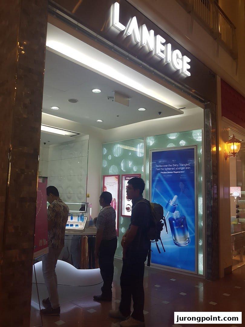 The illuminated entrance of a LANEIGE beauty shop, showcasing its branding and interior with customers.