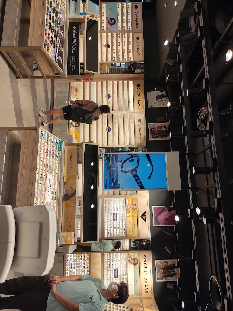 An interior view of a Lenskart store showcasing various eyewear displays and customers browsing.