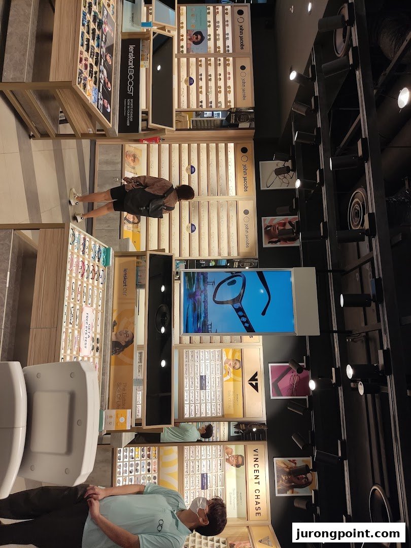 An interior view of a Lenskart store showcasing various eyewear displays and customers browsing.