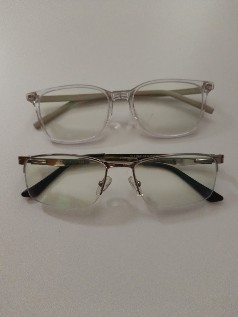 Two pairs of stylish eyeglasses, one clear-framed and one semi-rimless, displayed on a white surface.