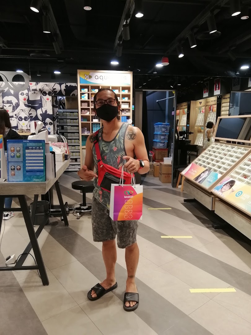 A customer stands inside a Lenskart store, holding a branded shopping bag after a purchase.