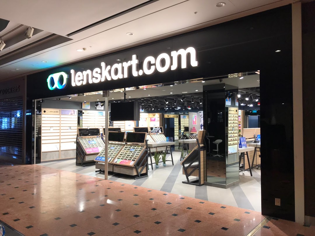 The Lenskart shop front features a prominent black facade with its illuminated logo and a clear view of eyewear displays inside.