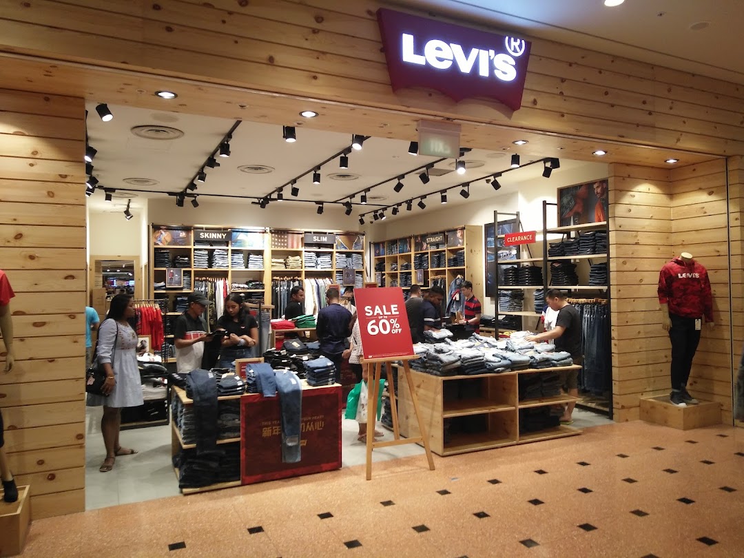 Customers browse denim and apparel inside a well-lit Levi's store featuring a prominent sale.