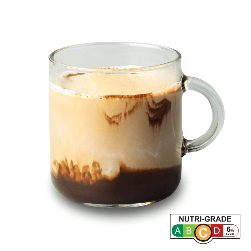 A clear glass mug holds a layered coffee or chocolate drink with cream and a Nutri-Grade label.