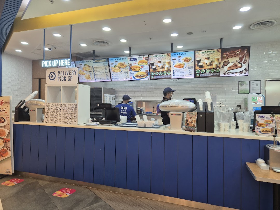 An interior view of Long John Silver's counter with staff and digital menu boards displaying various food options.