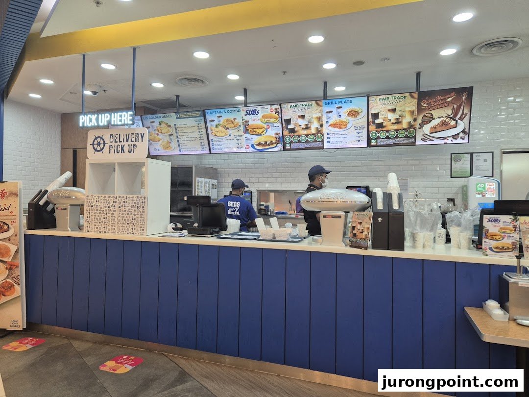 An interior view of Long John Silver's counter with staff and digital menu boards displaying various food options.