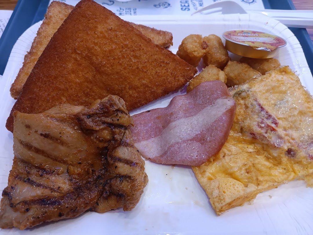 A hearty breakfast platter featuring grilled chicken, bacon, omelet, hash browns, and toast on a white tray.