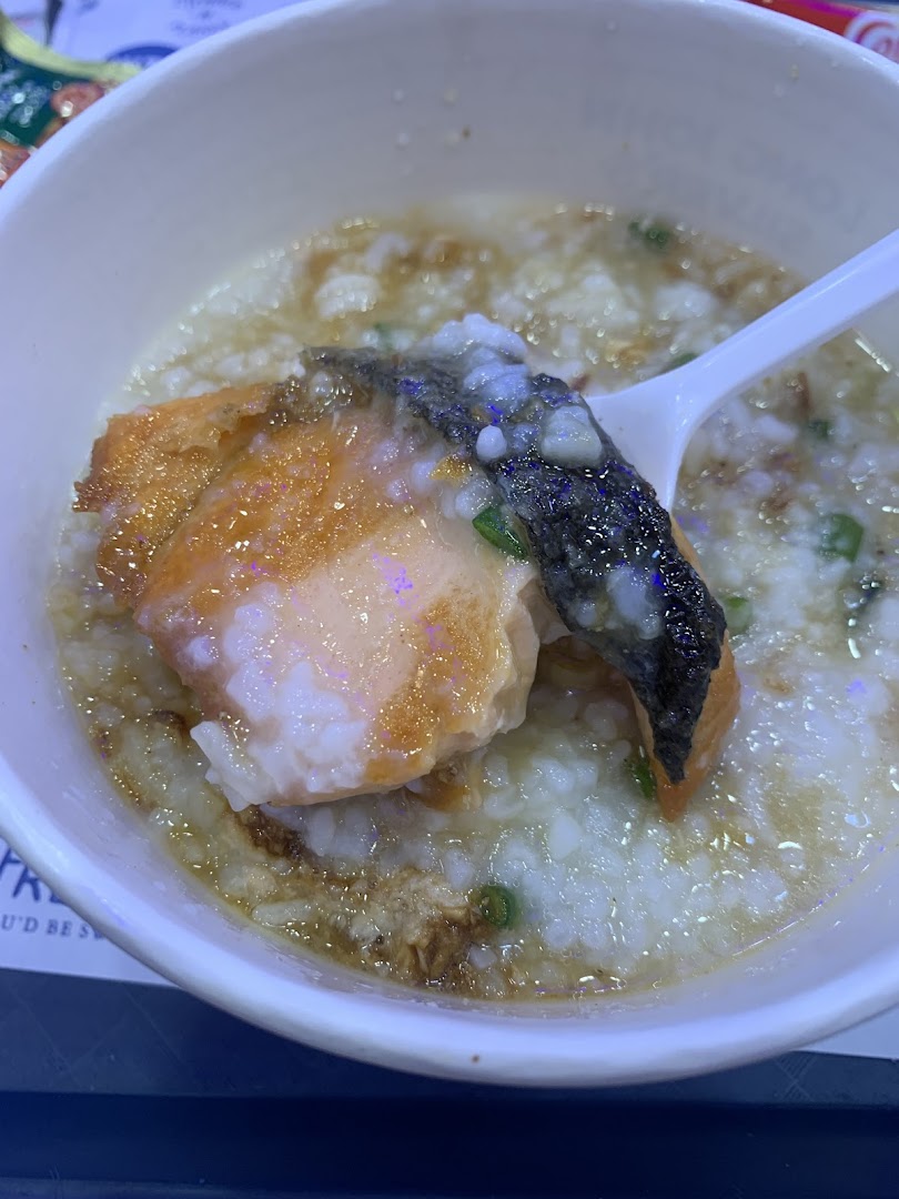 A close-up of a comforting bowl of congee topped with a large piece of savory salmon.