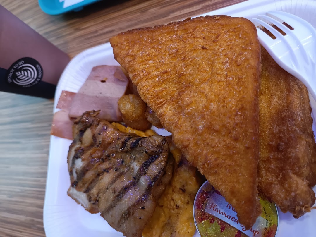 A close-up of a hearty breakfast platter featuring fried toast, grilled chicken, and ham.