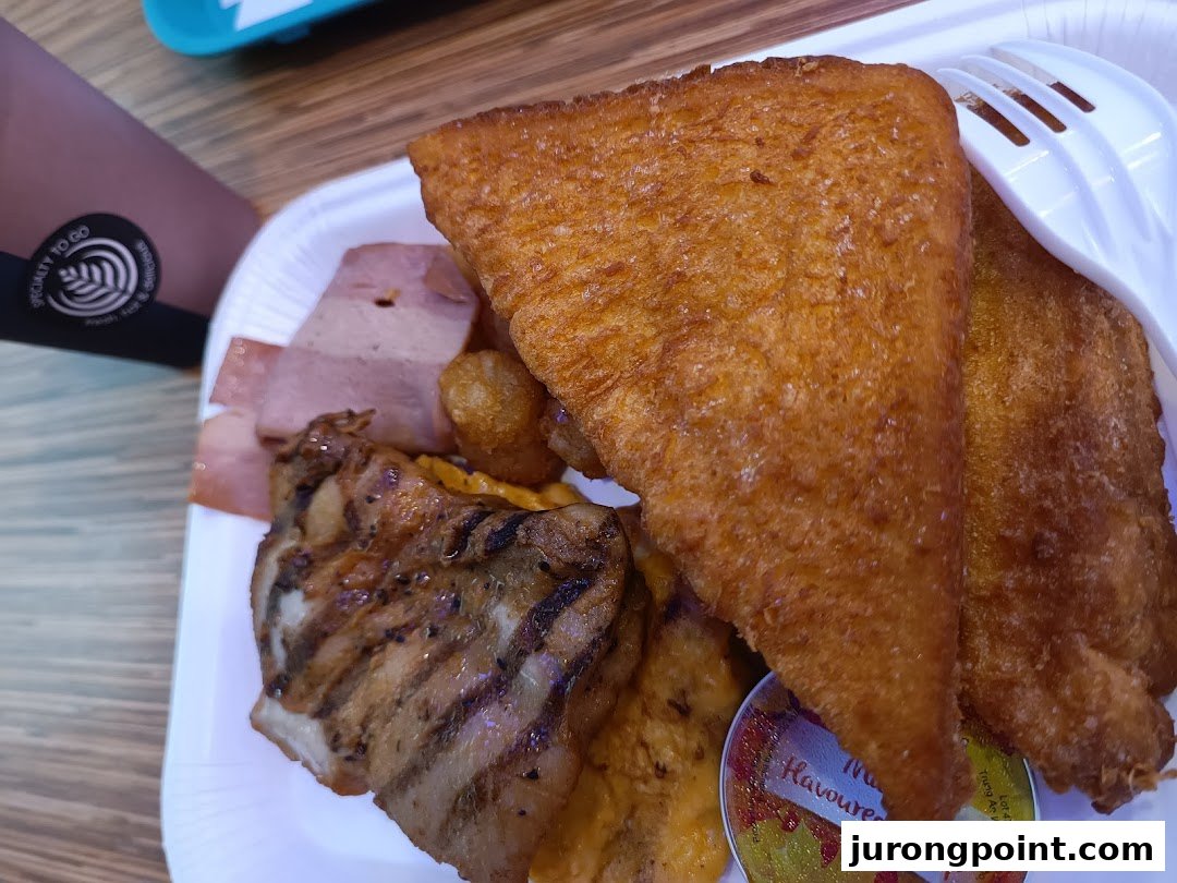 A close-up of a hearty breakfast platter featuring fried toast, grilled chicken, and ham.