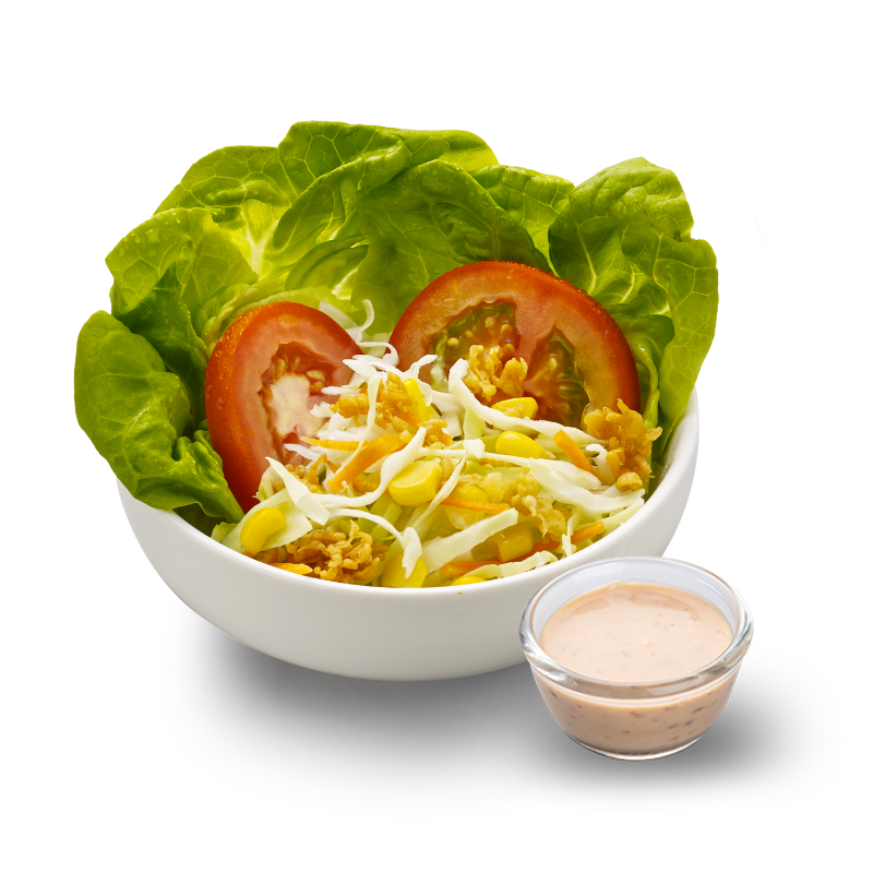 A fresh garden salad featuring lettuce, tomato, cabbage, corn, and crispy toppings, served with a side of dressing.