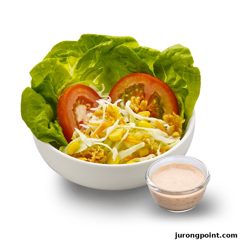 A fresh garden salad featuring lettuce, tomato, cabbage, corn, and crispy toppings, served with a side of dressing.