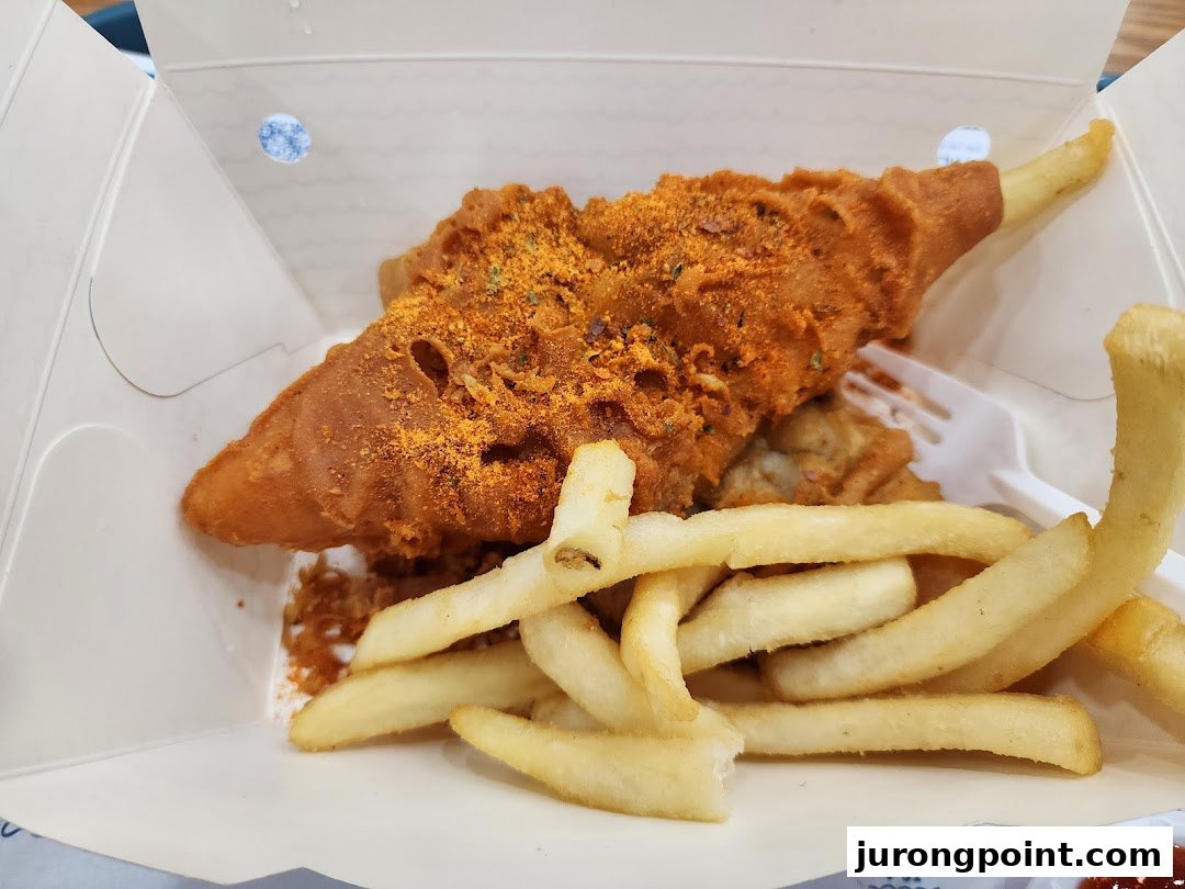 A close-up of crispy, seasoned fried fish and golden french fries in a takeout box.