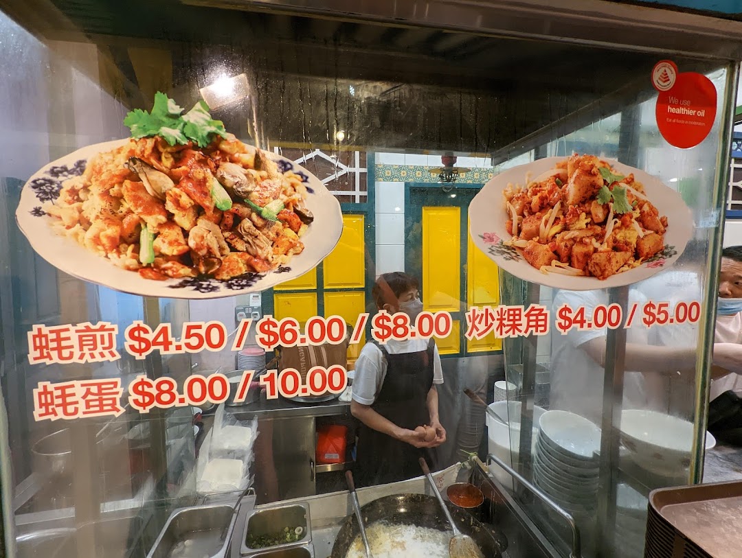 A hawker stall's menu board displaying popular local dishes like Oyster Omelette and Fried Radish Cake with prices.