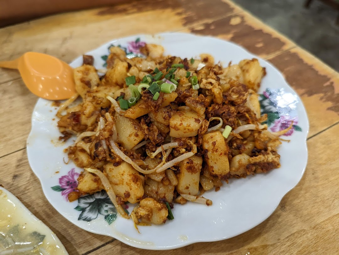 A plate of delicious fried carrot cake (chai tow kway) with bean sprouts and spring onions.