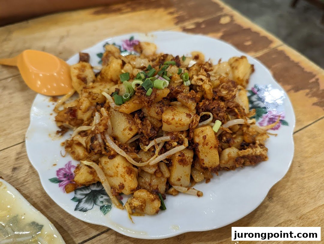 A plate of delicious fried carrot cake (chai tow kway) with bean sprouts and spring onions.