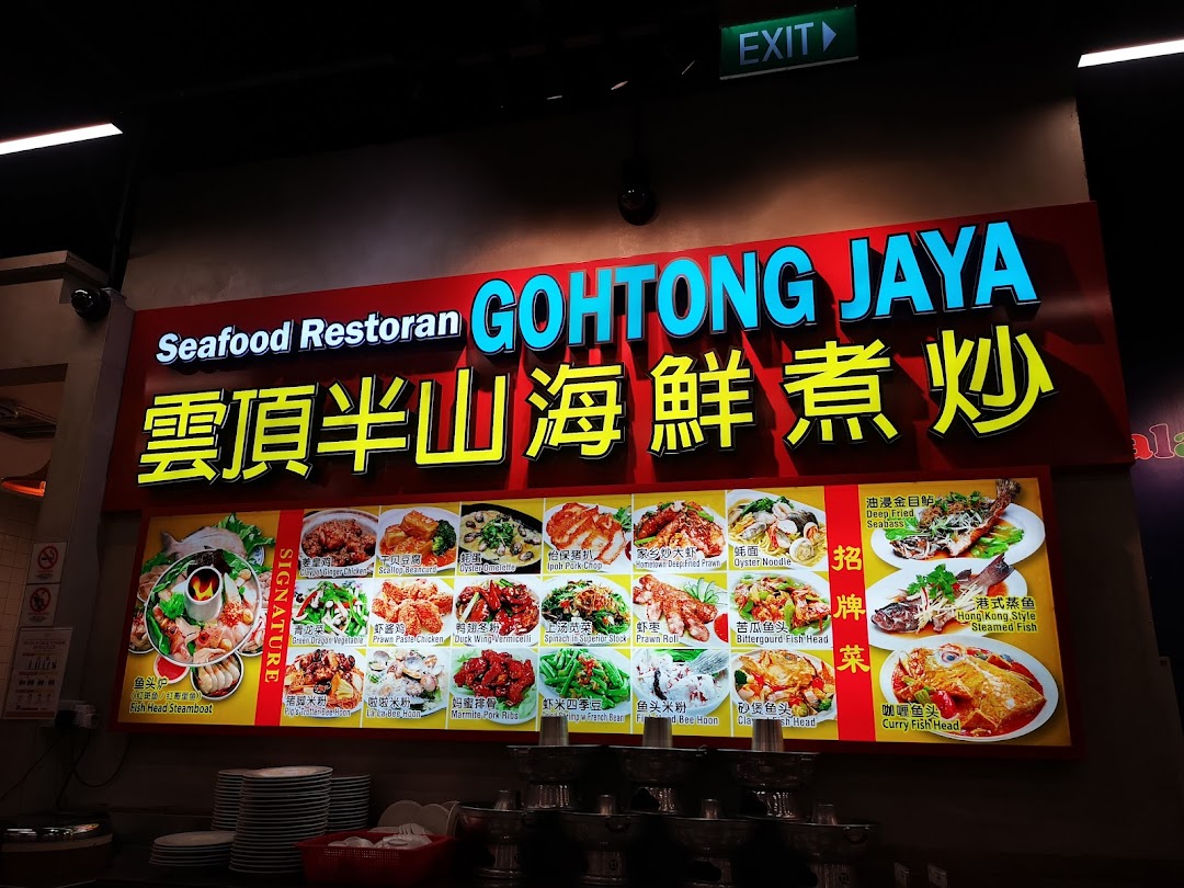 A large illuminated sign for Seafood Restoran GOHTONG JAYA, displaying various seafood and local dishes with photos.